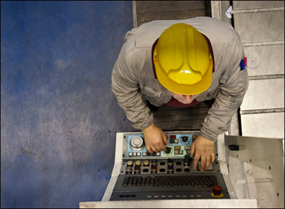 Factory worker using computer to operate machine