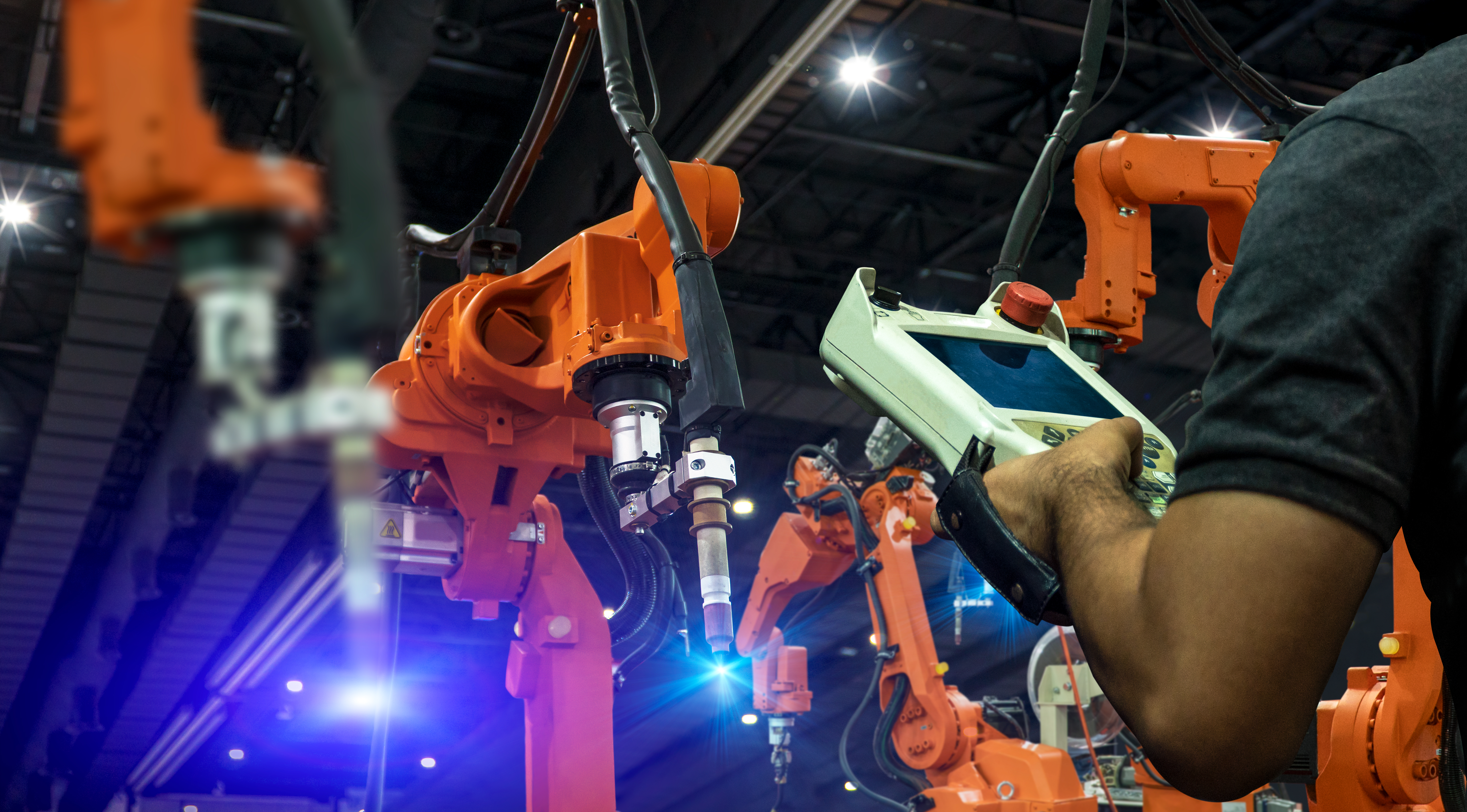 A man's hand controlling robotic arms through controller