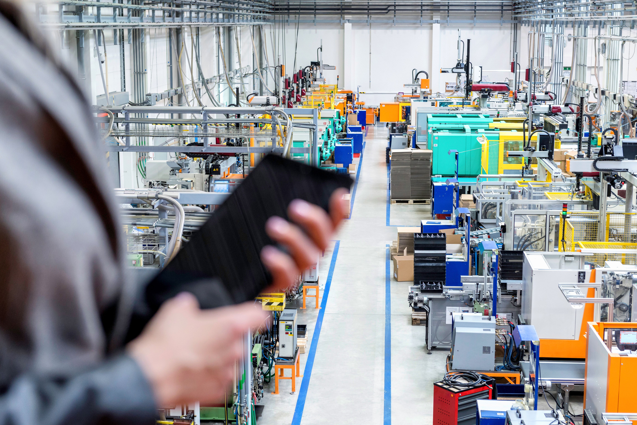 A hand holding tablet facing over a warehouse